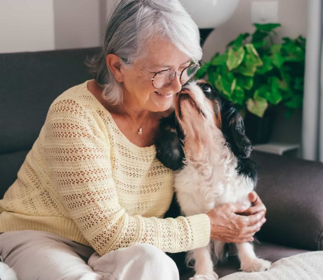 dog licking senior woman's cheek
