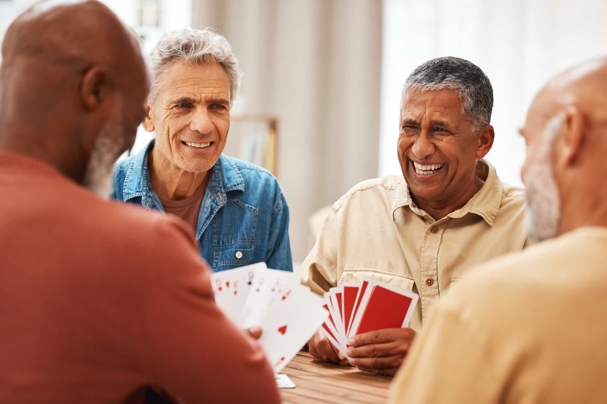 Group of guys playing cards while sitting at a table.