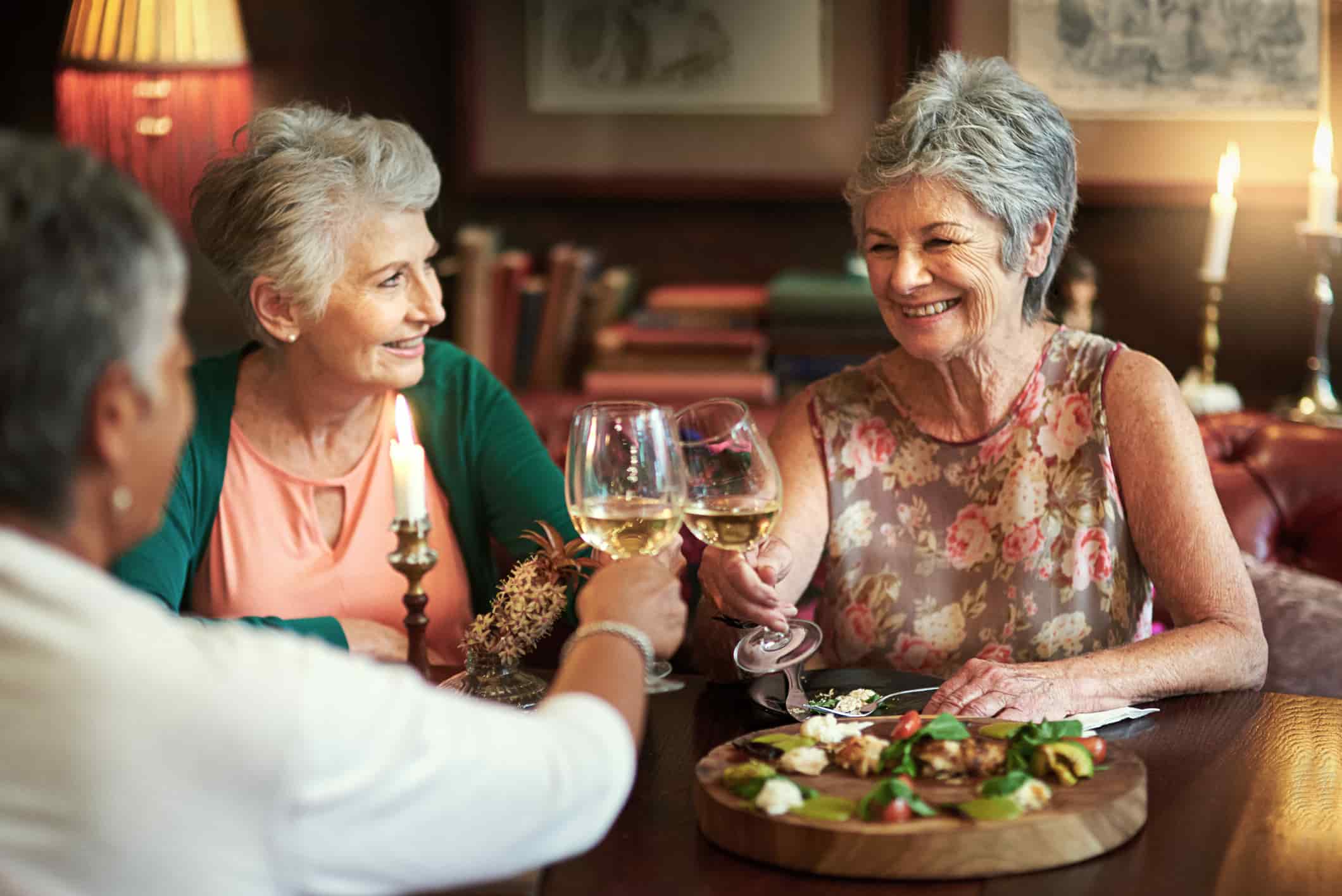 Women clinking wine glasses in a dining area.